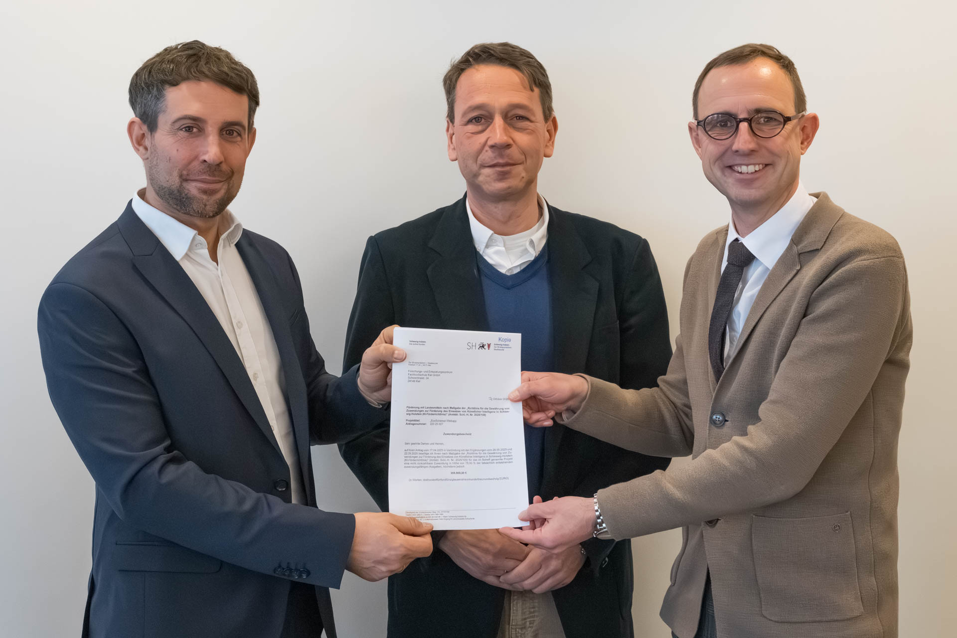Drei Männer zeigen ein Dokument in die Kamera